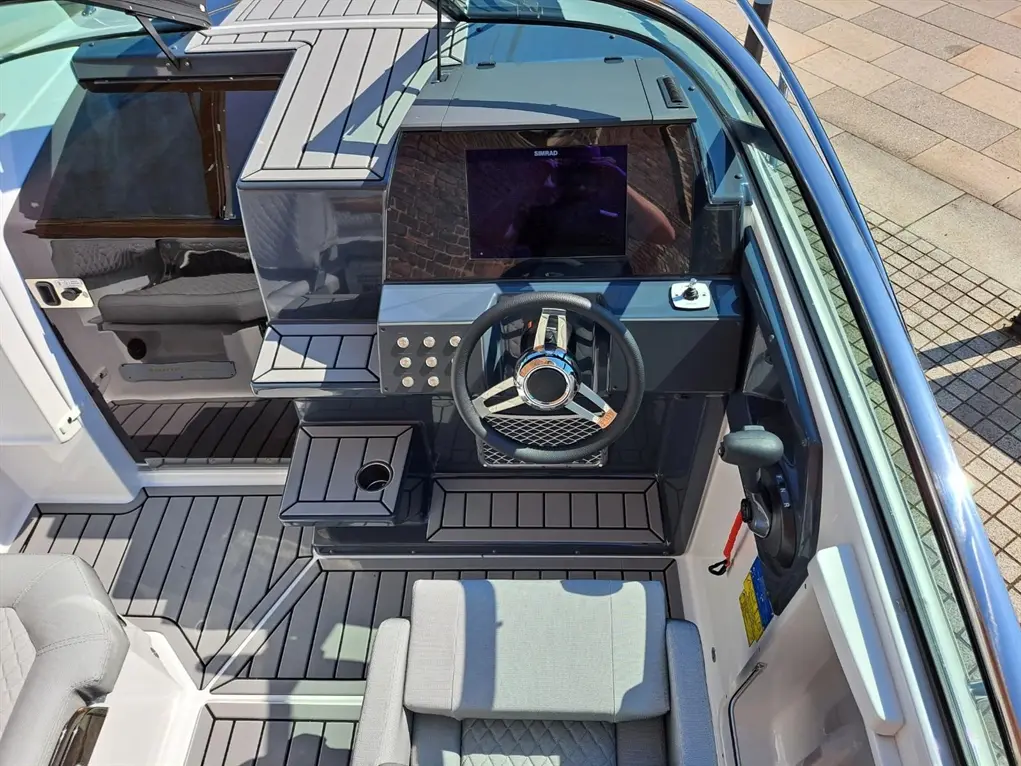 A modern boat's dashboard showcases a steering wheel, monitor, and control panel, set on a stylish deck with grey flooring.